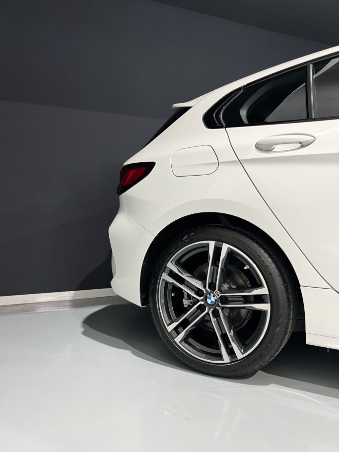 Vista lateral de un coche blanco con llantas de diseño deportivo.